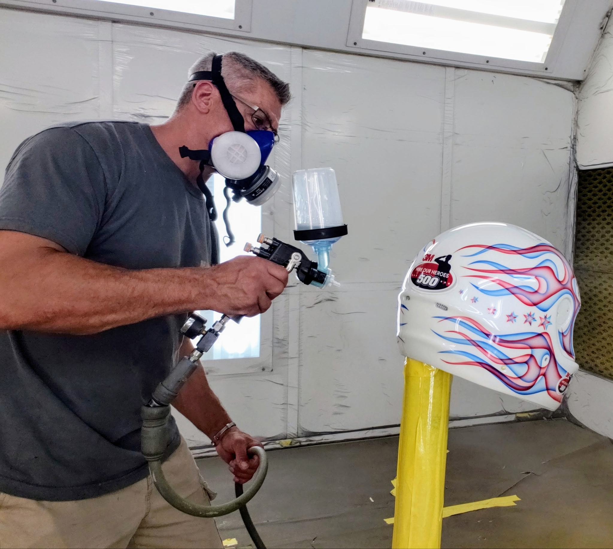 Bonafide technician painting a custom helmet in the spray booth